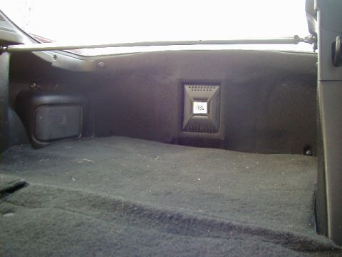 1994 Ford Probe - The rear cargo area of a car features a carpeted floor and a mounted speaker.
