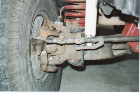 1990 Ford Bronco - Detail of the front suspension system, including the tire, steering linkage, coil spring, and shock absorber.