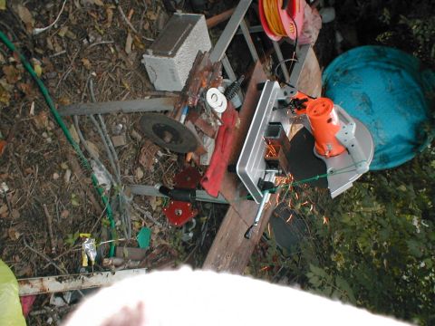 1979 Ford Bronco - Chop saw in action, cutting metal with sparks. Debris and tools are scattered around the work area.