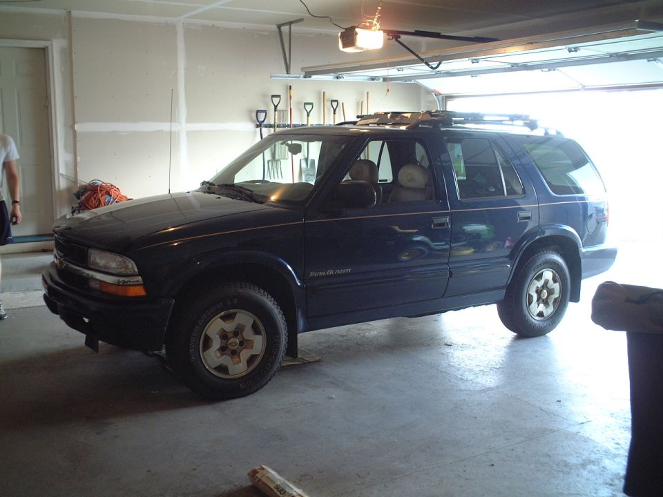 Dark blue Chevrolet Blazer SUV parked in a garage with roof rack and white-spoke alloy wheels
