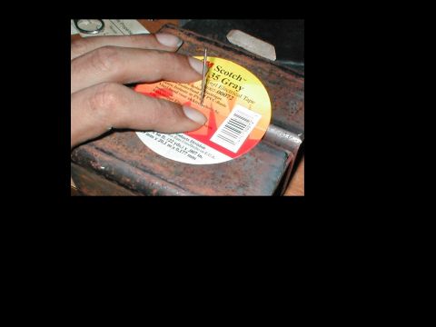 1979 Ford Bronco - Close-up of a hand using a needle on a roll of Scotch 35 Gray vinyl electrical tape.
