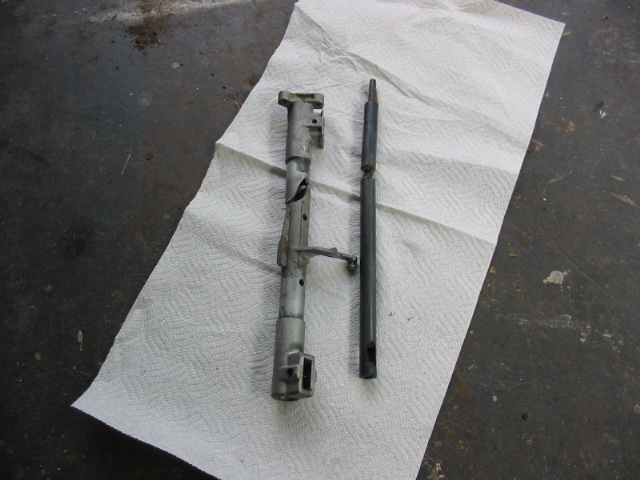 Two metal automotive parts laid out on paper towels on a concrete floor