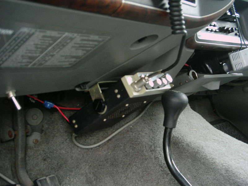 Interior view of a CB radio mounted under the dashboard and a black gear shifter