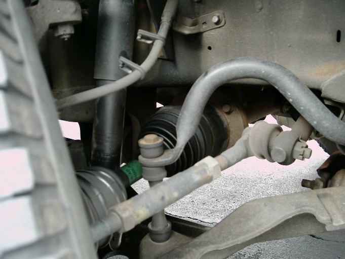 Close-up of truck's front suspension parts, including shock, tie rod, and CV joint boot