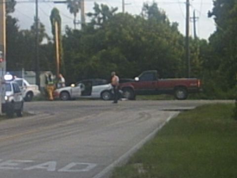 1991 Ford Probe - Several vehicles and people are gathered at a street intersection.