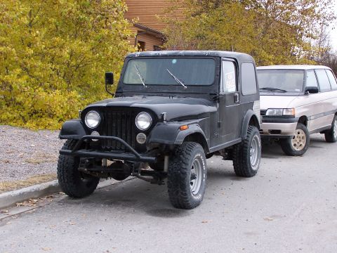1983 Jeep CJ7 - Black 1983 Jeep CJ7 parked on a street with another vehicle behind it.