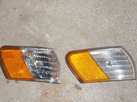 1998 Ford Taurus - Two vehicle corner lights, one amber and one clear, are shown against a concrete surface.