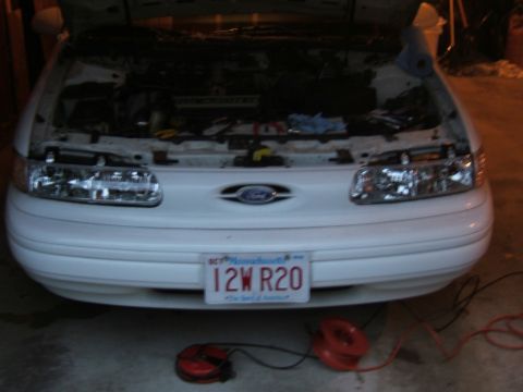 1998 Ford Taurus - Front view of a white 1998 Ford Taurus with its hood open, revealing the engine bay.