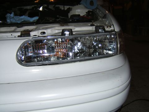 1998 Ford Taurus - Front headlight assembly on a 1998 Ford Taurus with the hood open.