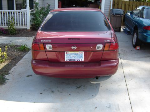 1998 Nissan Sentra - Rear view of a red 1998 Nissan Sentra GXE sedan, parked next to another vehicle.