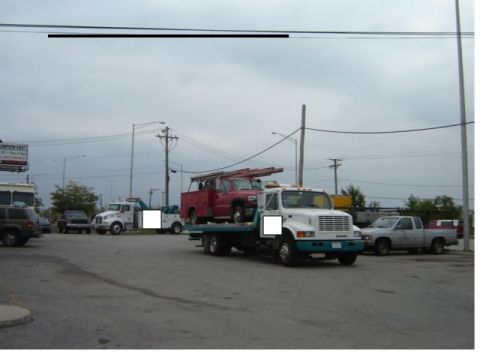 1992 Ford Bronco - A tow truck transports a red pickup truck under an overcast sky.