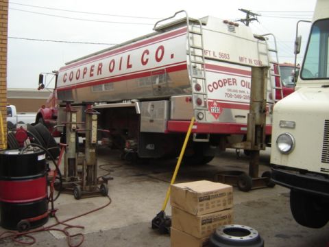 1992 Ford Bronco - A Cooper Oil Co. tanker truck is parked in a service bay next to a white truck.