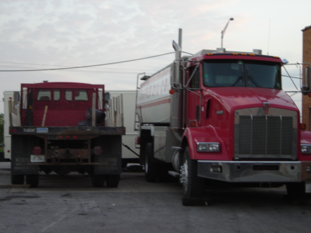 Red semi-truck and a red flatbed truck parked side-by-side