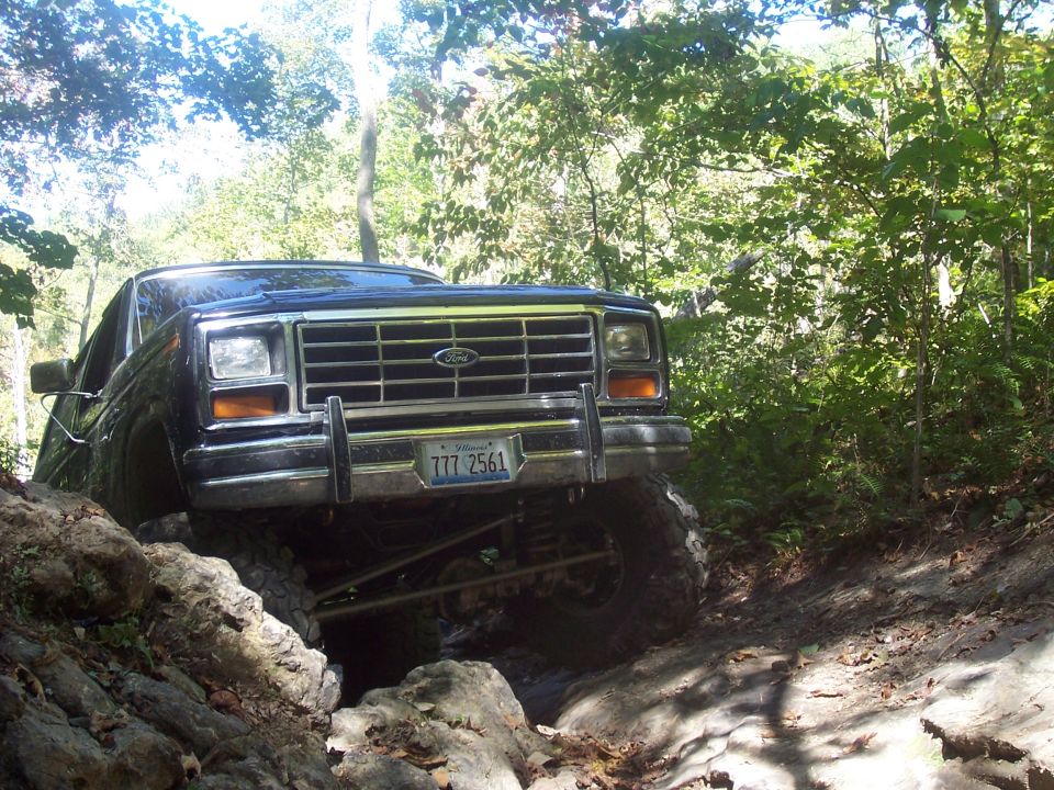 Ford Bronco navigating a rocky, wooded trail