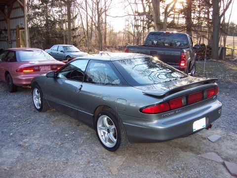 1996 Ford Probe - A gray Ford Probe is parked next to a pink Ford Probe and a pickup truck.
