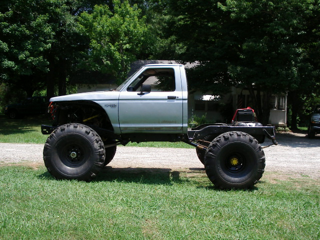Side view of a custom lifted truck with oversized tires and a shortened bed