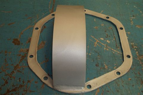 1983 Ford Bronco - Differential cover and gasket shown on a teal surface with Supermotors.net watermark.
