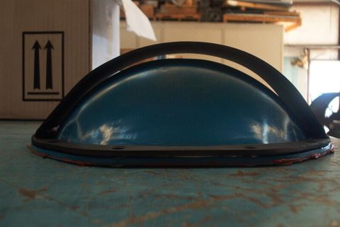 1983 Ford Bronco - A blue automotive part with black trim and red sealant is shown on a teal surface.