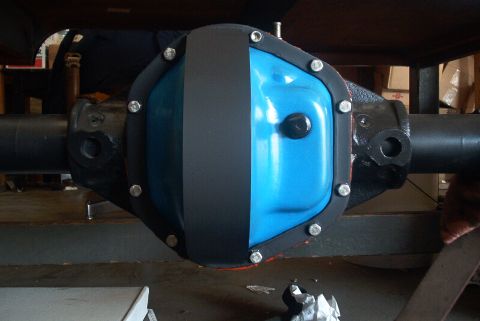 1983 Ford Bronco - A differential cover, split between blue and black paint, is attached to a vehicle axle.