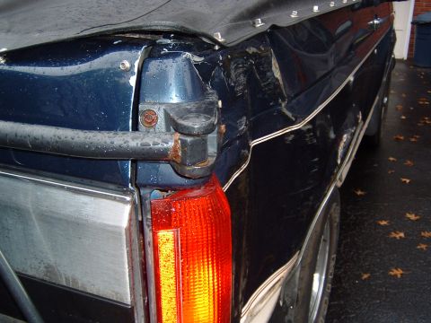 1993 Ford Bronco - Damage is visible on the rear corner of this dark blue SUV, which features a soft top and a red taillight.