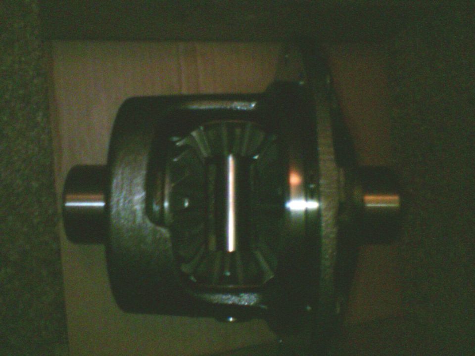 Open differential carrier with ring gear and spider gears sitting in a cardboard box on carpet