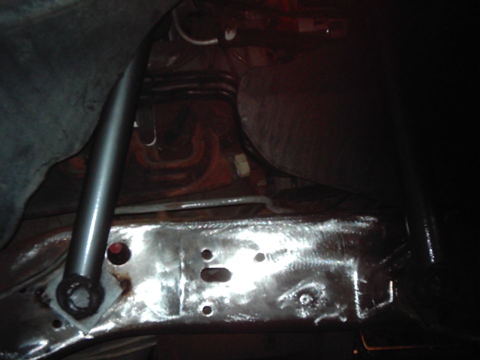 Close-up of a shiny, bare metal vehicle frame with a shock absorber and brake lines visible
