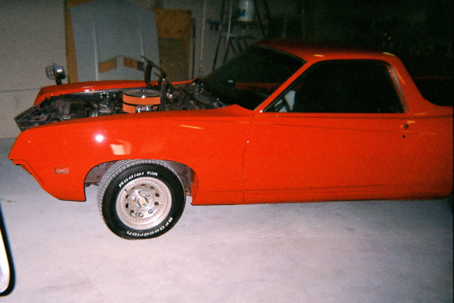 Orange Ranchero-style coupe utility in garage with hood up, side view
