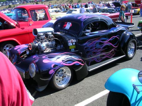 1996 Ford Probe - A custom hot rod with flame graphics is displayed at a car show.