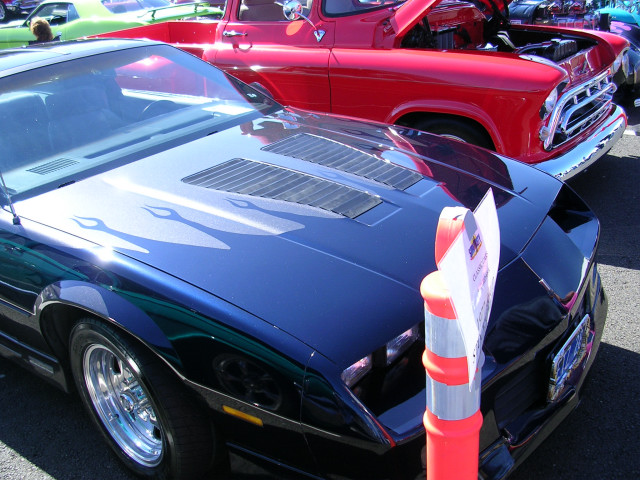 Dark blue car with flame decals on hood, parked next to a red pickup truck