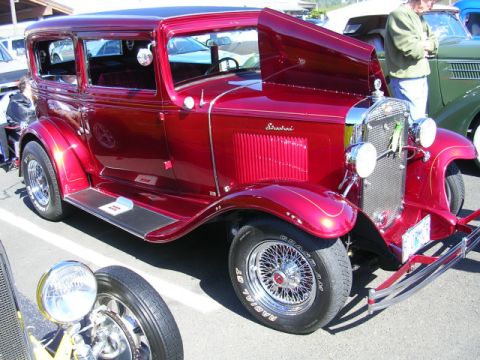 1996 Ford Probe - A red vintage sedan is displayed with its hood open at a car show, parked next to other vehicles.