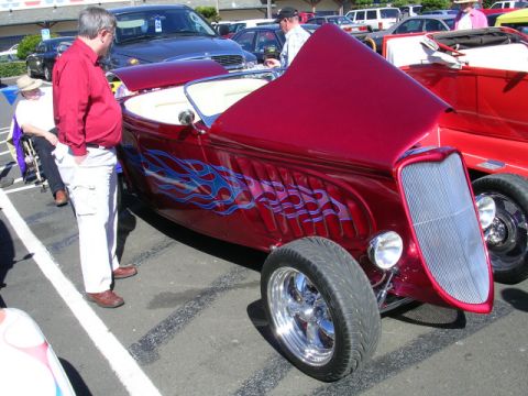 1996 Ford Probe - A custom hot rod with flame decals and its hood open is displayed at a car show.