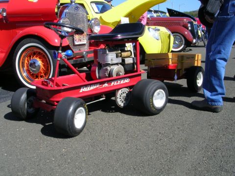 1996 Ford Probe - A custom-built red wagon with an engine and trailer is parked in front of several classic cars.