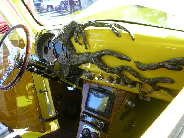 Yellow dashboard with a dark, sculpted tree branch design. Features a wood-rimmed steering wheel and a central screen