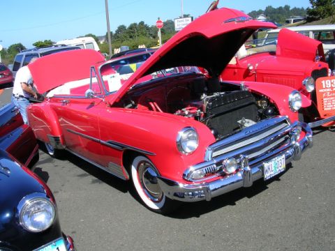 1996 Ford Probe - A red convertible is displayed with its hood open at a car show, alongside other vehicles.