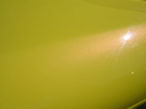 1996 Ford Probe - Close-up of a yellow metallic car body panel, showing paint texture and reflections.
