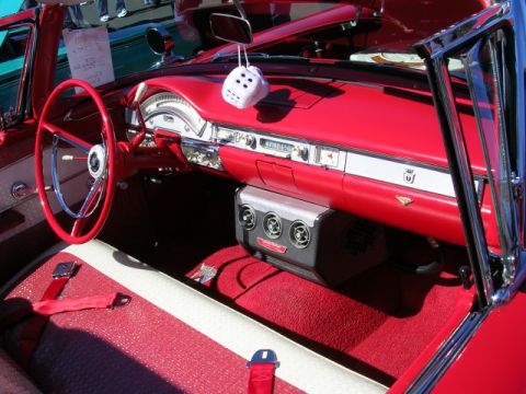 1996 Ford Probe - The interior of a vintage red car features a classic steering wheel, fuzzy dice, and a modern air conditioning unit.