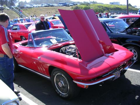 1996 Ford Probe - A classic red convertible is displayed with its hood open at an outdoor car show.