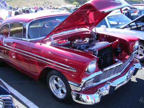 1996 Ford Probe - A gleaming red 1956 Chevrolet Bel Air coupe is displayed with its hood open at a car show.