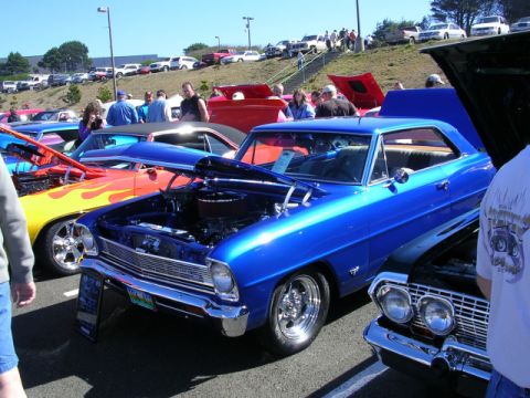 1996 Ford Probe - A blue classic car is displayed with its hood open at a car show, alongside other vehicles.