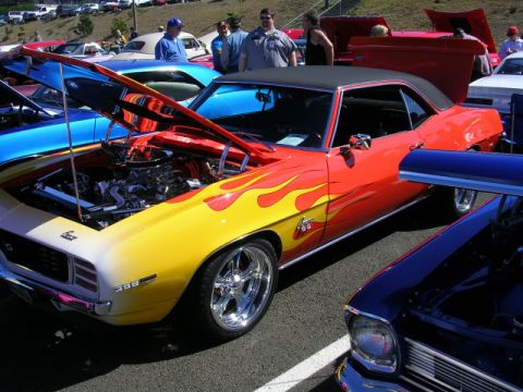 1996 Ford Probe - A classic 1969 Chevrolet Camaro SS with a custom flame paint job is displayed at a car show.