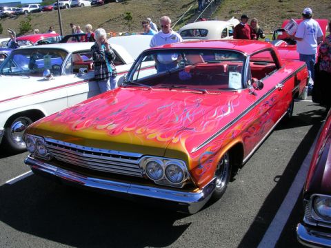 1996 Ford Probe - A classic Chevrolet Impala with custom flame paint is displayed at a car show.
