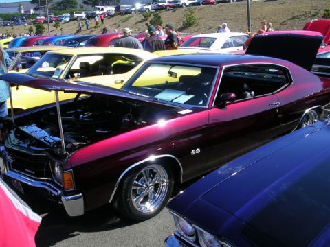 1996 Ford Probe - A maroon muscle car, identified by its SS badging, is displayed with its hood open at a car show, alongside other vehicles.