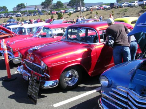 1996 Ford Probe - A red 1955 Chevrolet is displayed at a car show, with multiple other classic vehicles in the background.