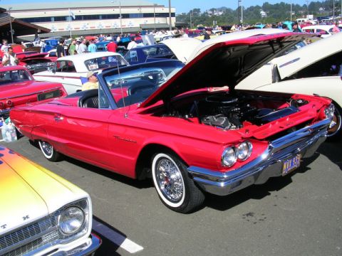 1996 Ford Probe - A bright red convertible is displayed with its hood up at an outdoor car show, surrounded by other vehicles.