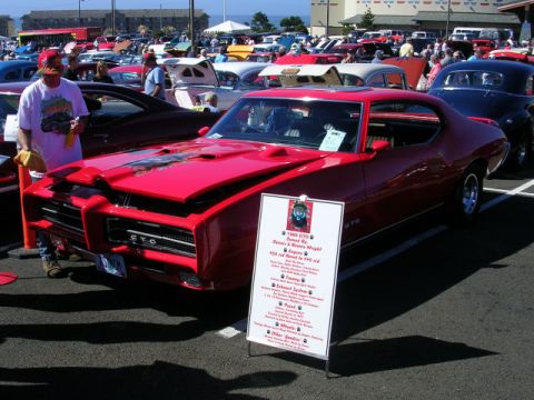1996 Ford Probe - A red 1969 Pontiac GTO is displayed at a car show with a descriptive sign next to it.