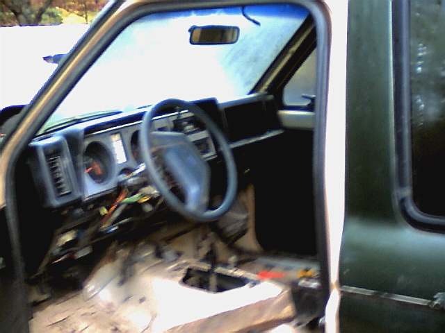Interior of a 1987 Ford Bronco II with exposed wiring and removed floor panels