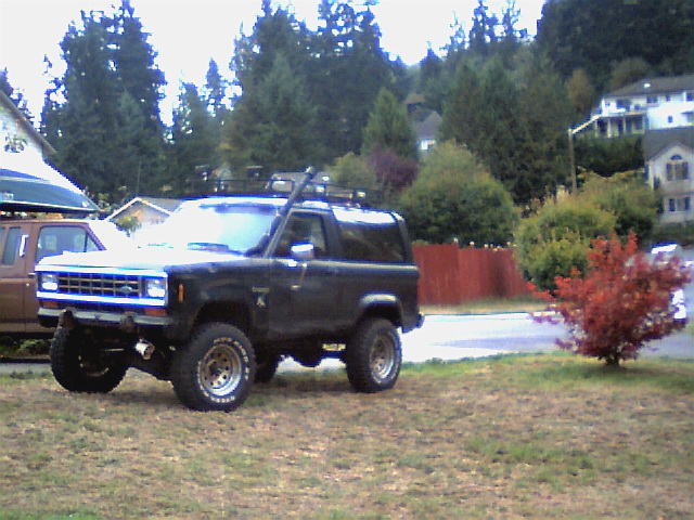 Lifted dark blue two-door Ford Bronco II with roof rack on mud-terrain tires