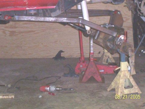 1994 Ford Bronco - Undercarriage of a vehicle being worked on, with suspension parts visible and tools on the ground.