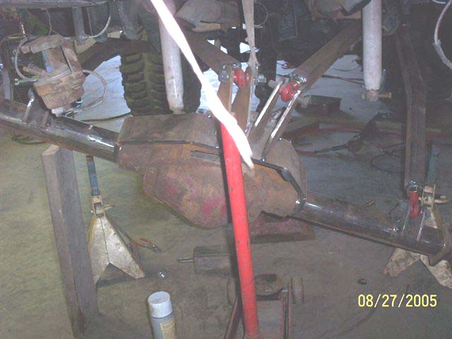 Vehicle's rear axle assembly on jack stands, showing suspension components and brake caliper