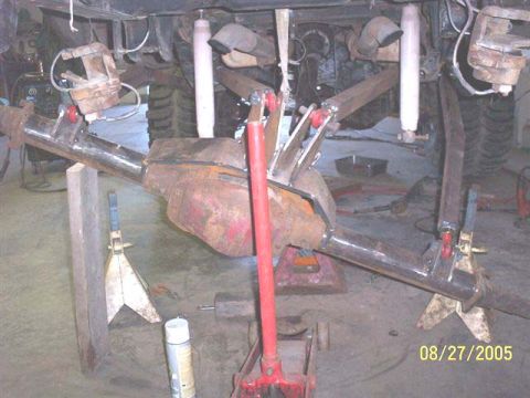 1994 Ford Bronco - Close-up of a vehicle's rear axle assembly and suspension components, supported by jack stands.
